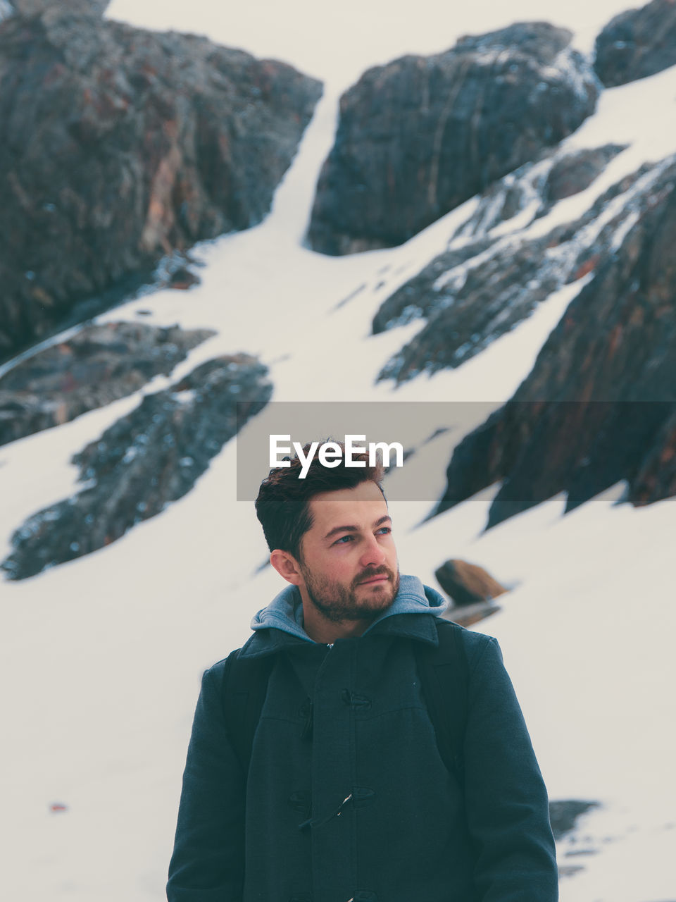 Man looking away against snowy rocks