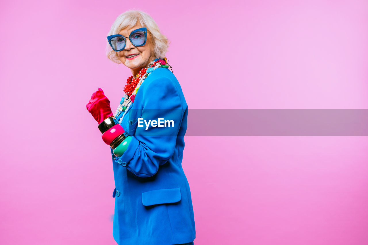 Portrait of senior woman gesturing against colored background