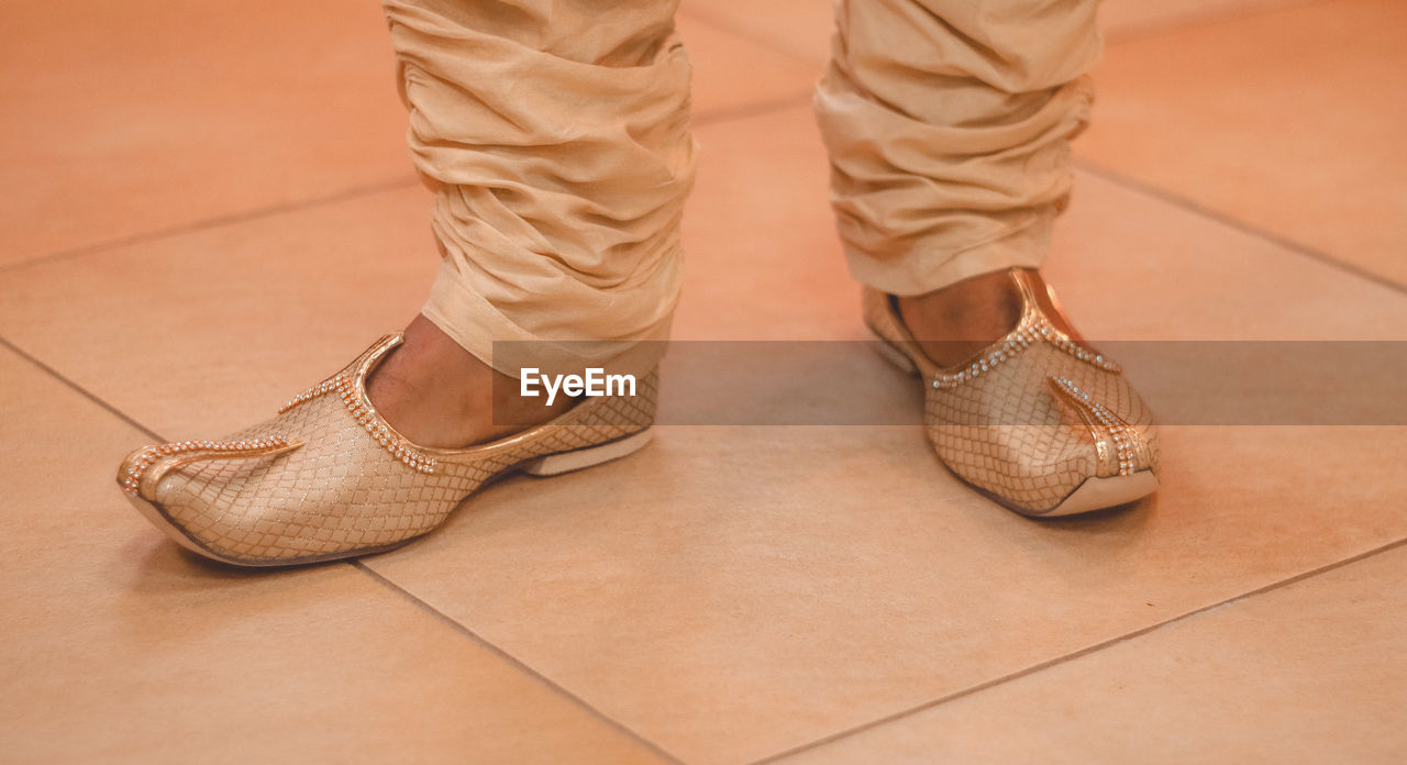Low section of man standing on tiled floor