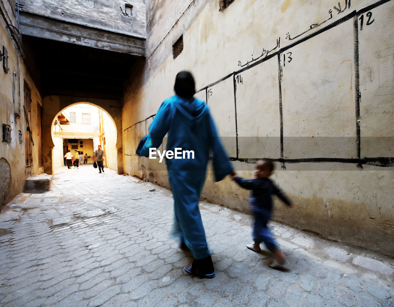 Blurred motion of mother with son walking by election wall