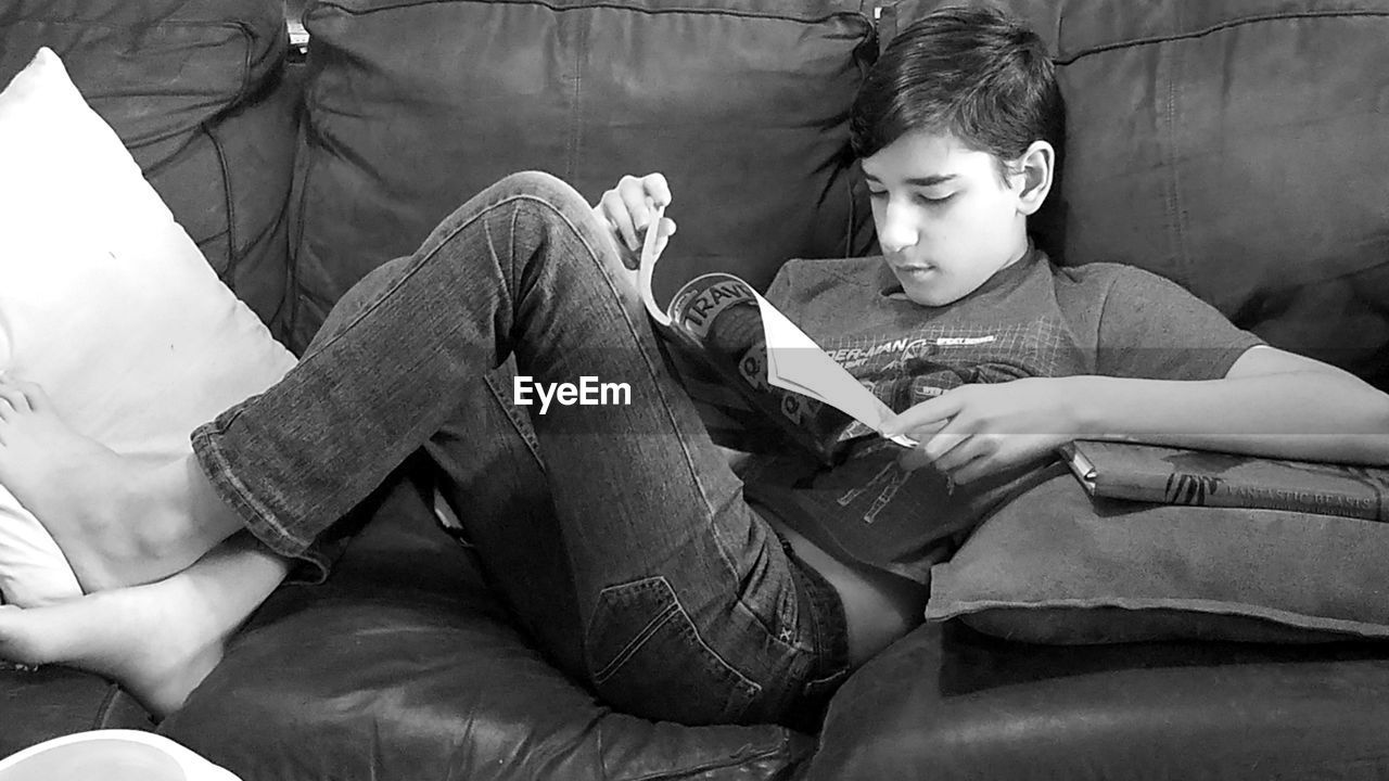 Rear view of boy looking at camera while sitting on sofa