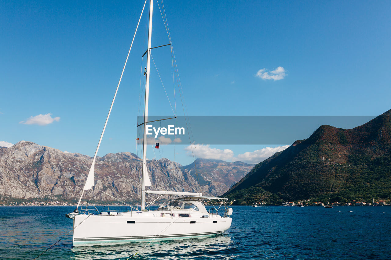 SAILBOAT SAILING IN SEA AGAINST SKY