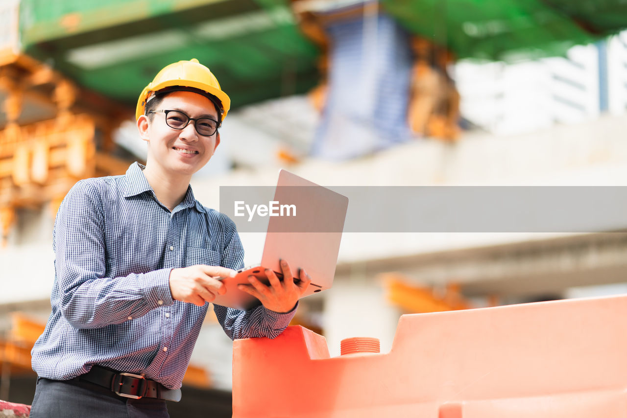 YOUNG MAN WORKING WITH ARMS RAISED