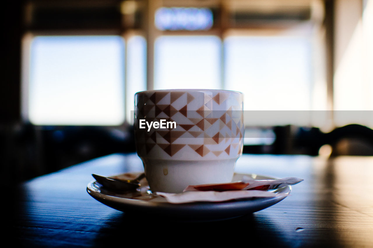 Coffee cup in plate on table at cafe