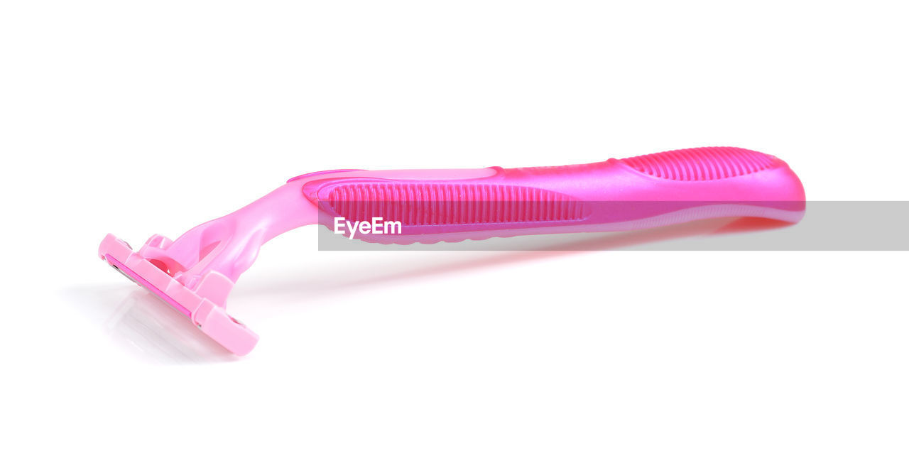 Close-up of pink colored razor over white background
