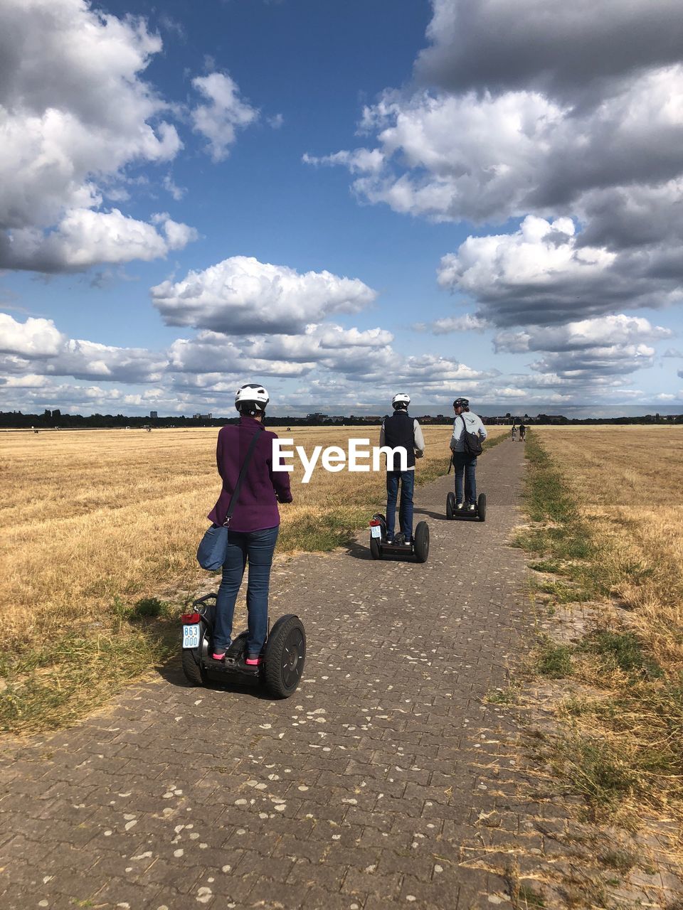 REAR VIEW OF FRIENDS ON ROAD AGAINST SKY