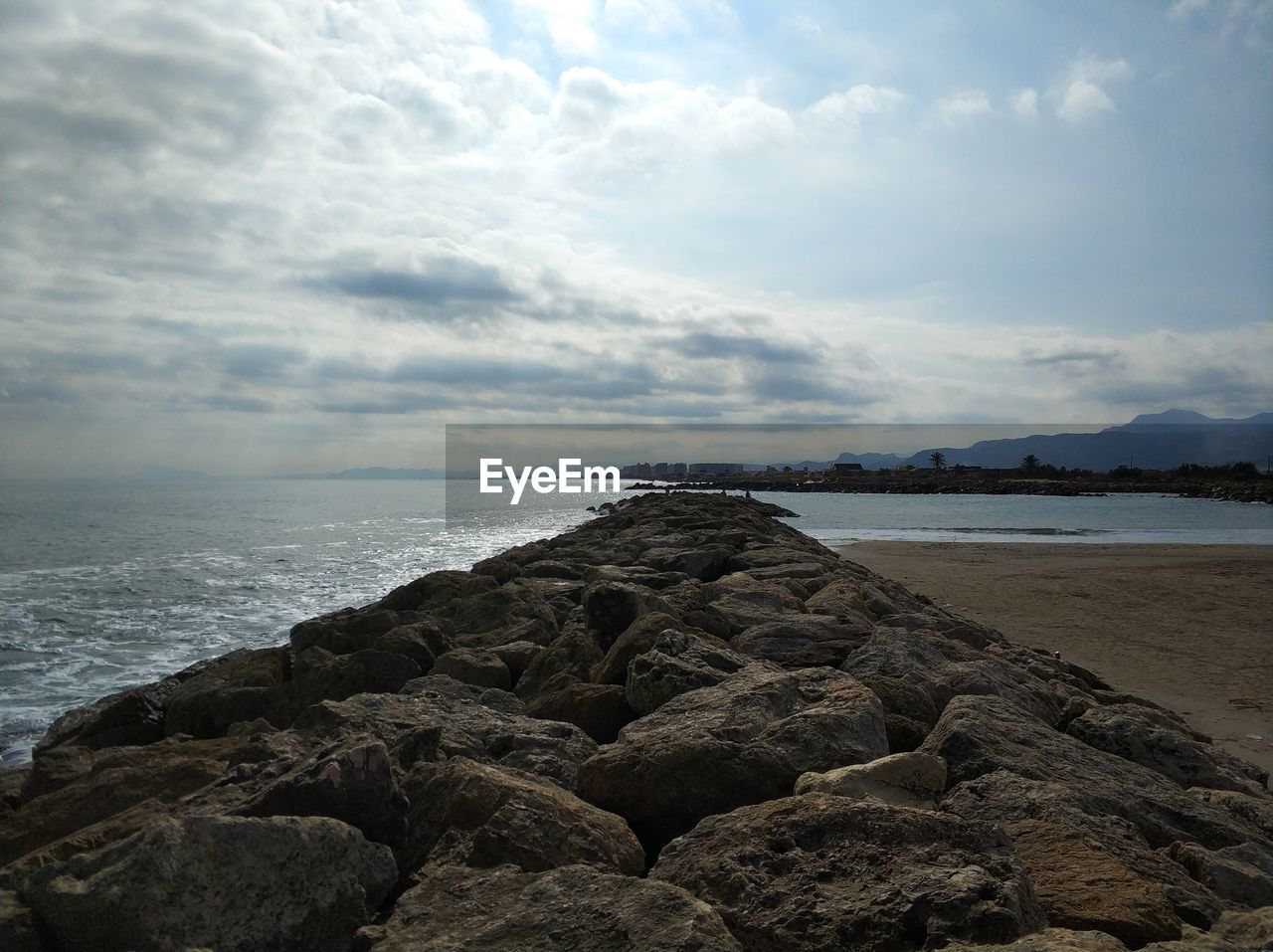 ROCKS ON BEACH AGAINST SKY