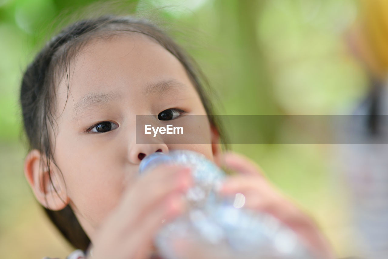 Close-up portrait of girl drinking water from bottle