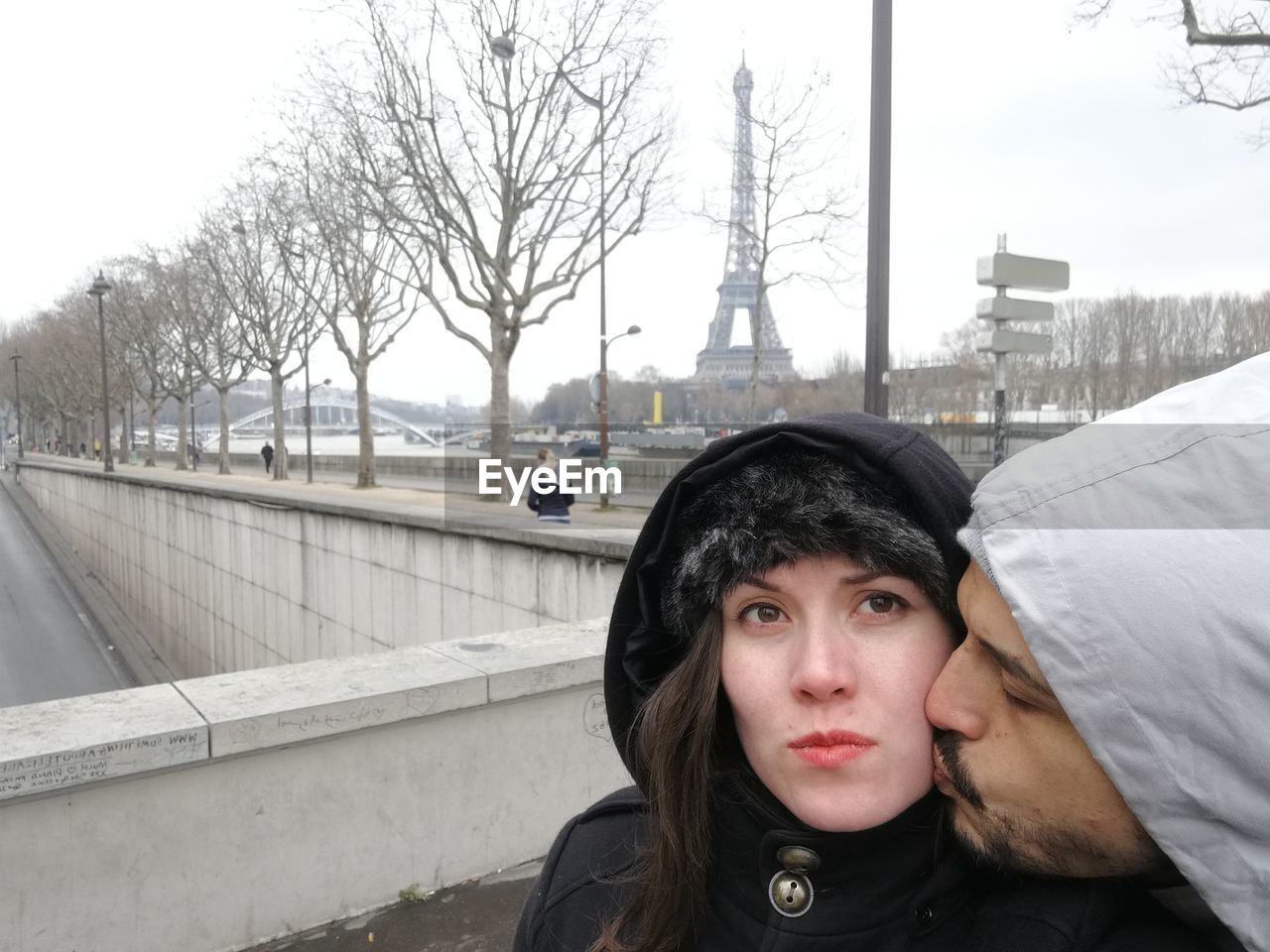 Man kissing woman while standing in city during winter