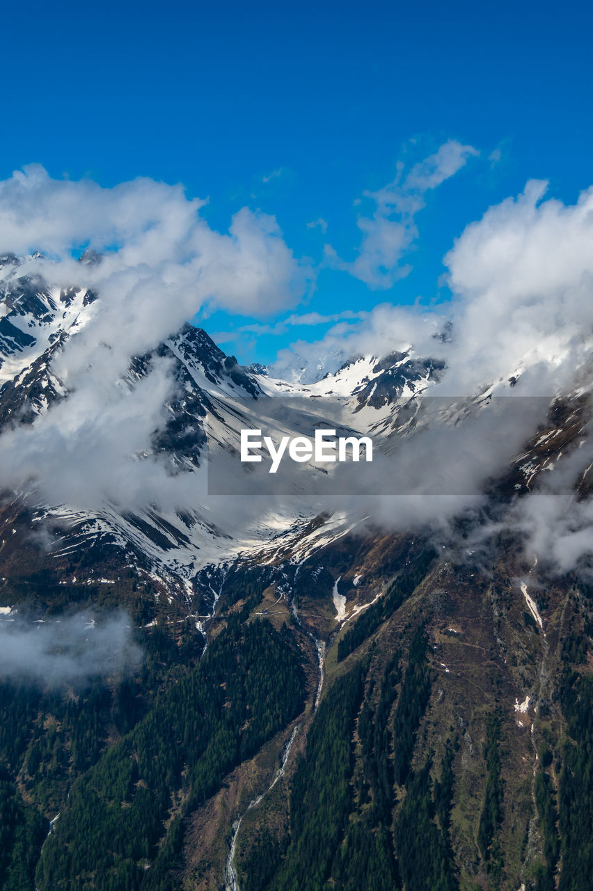 Scenic view of snowcapped mountains against blue sky