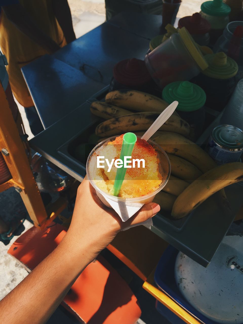 Cropped image of hand holding slushie in disposable cup at stall
