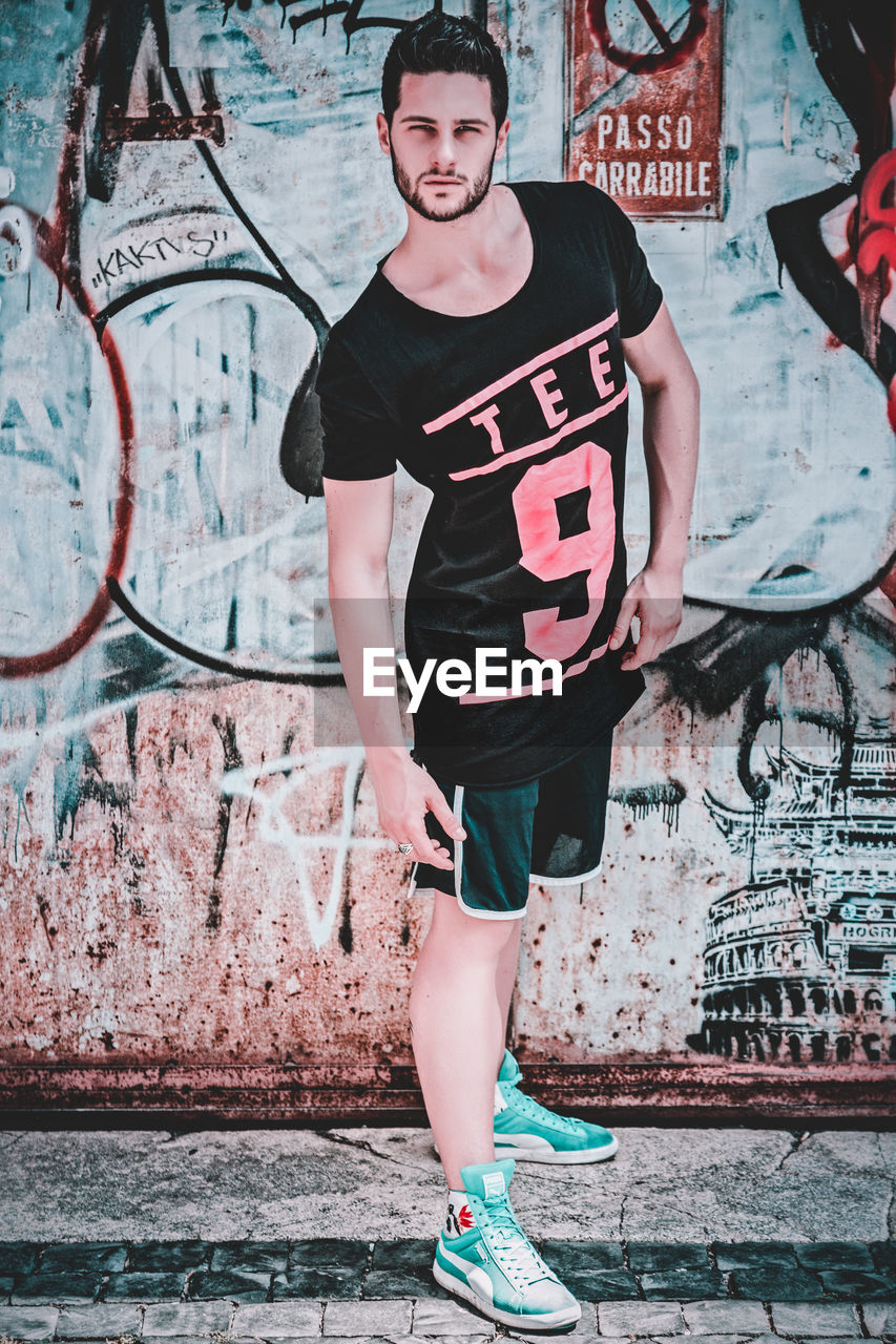 PORTRAIT OF TEENAGE BOY STANDING ON WALL