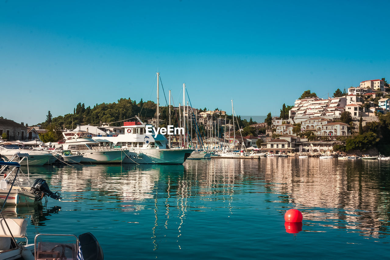 Boats in marina at harbor against clear blue sky