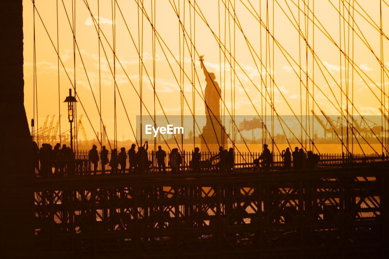Silhouette people visiting statue of liberty during sunset