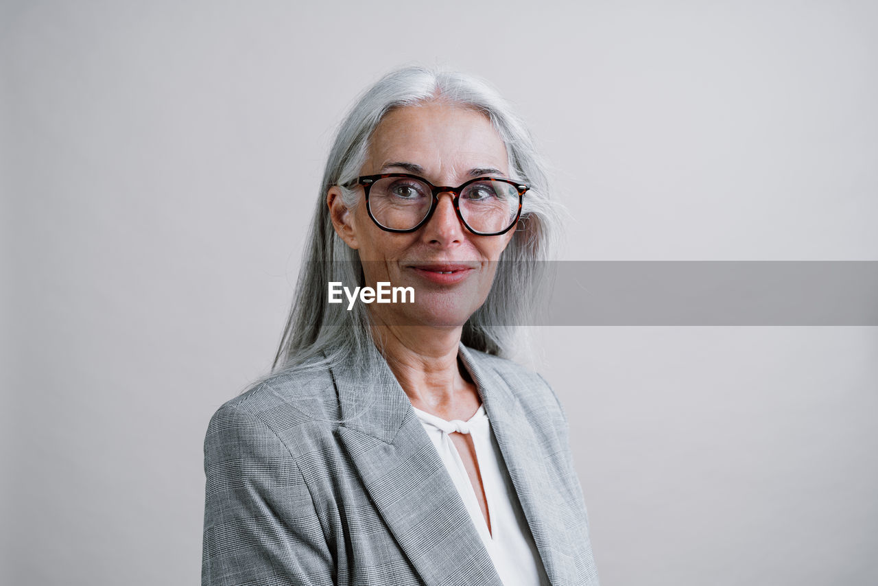 portrait of smiling young woman standing against white background