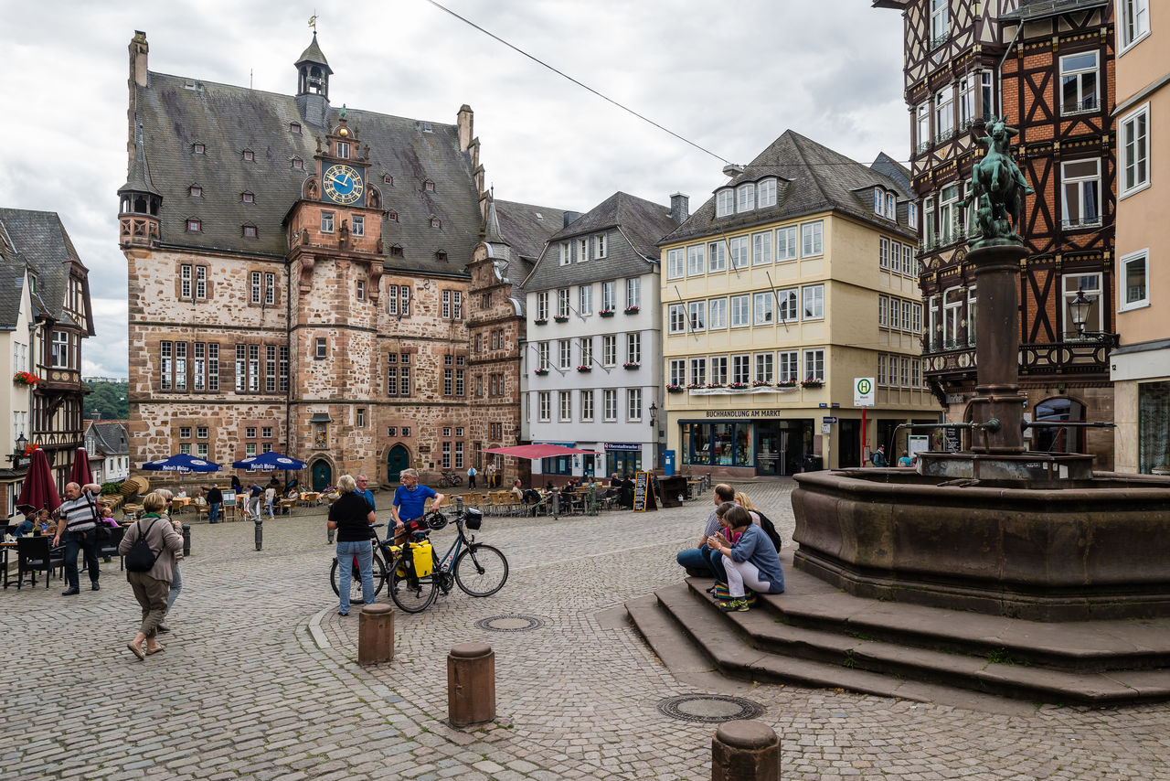 People walking in street by old buildings in marburg