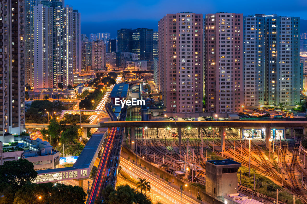 High angle view of illuminated city by buildings at night