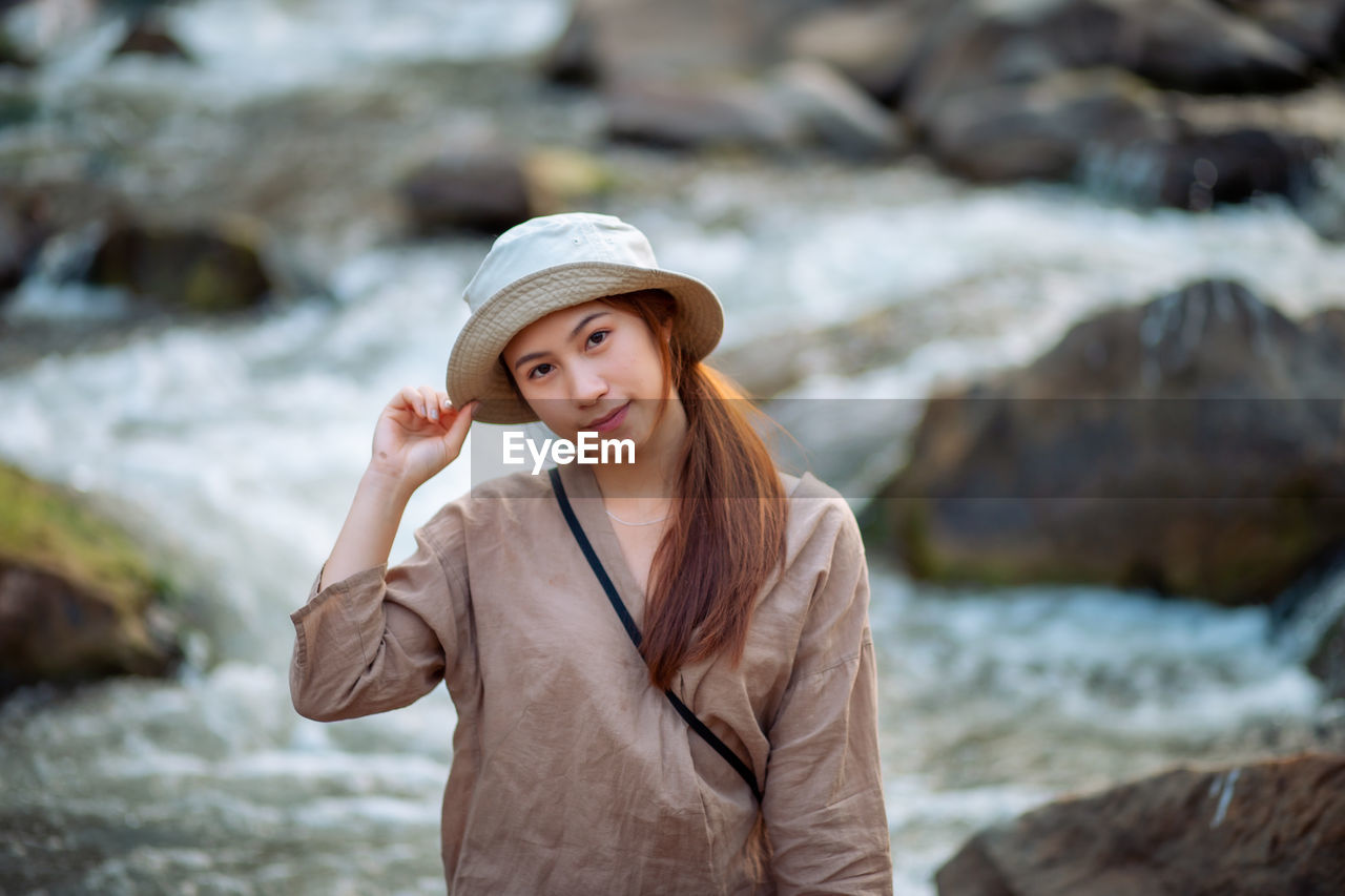 Portrait of beautiful young woman standing on rock