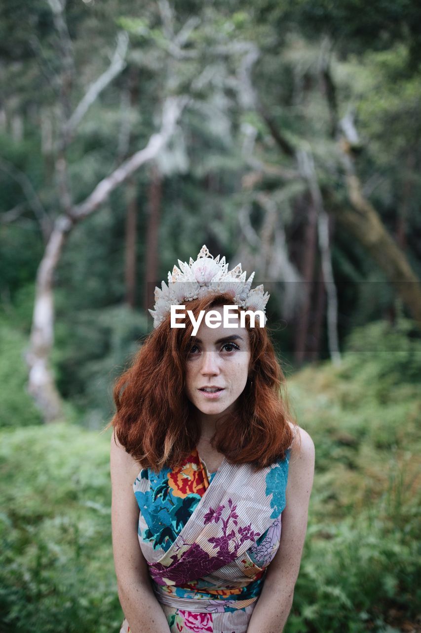 Portrait of redhead woman wearing headwear against trees