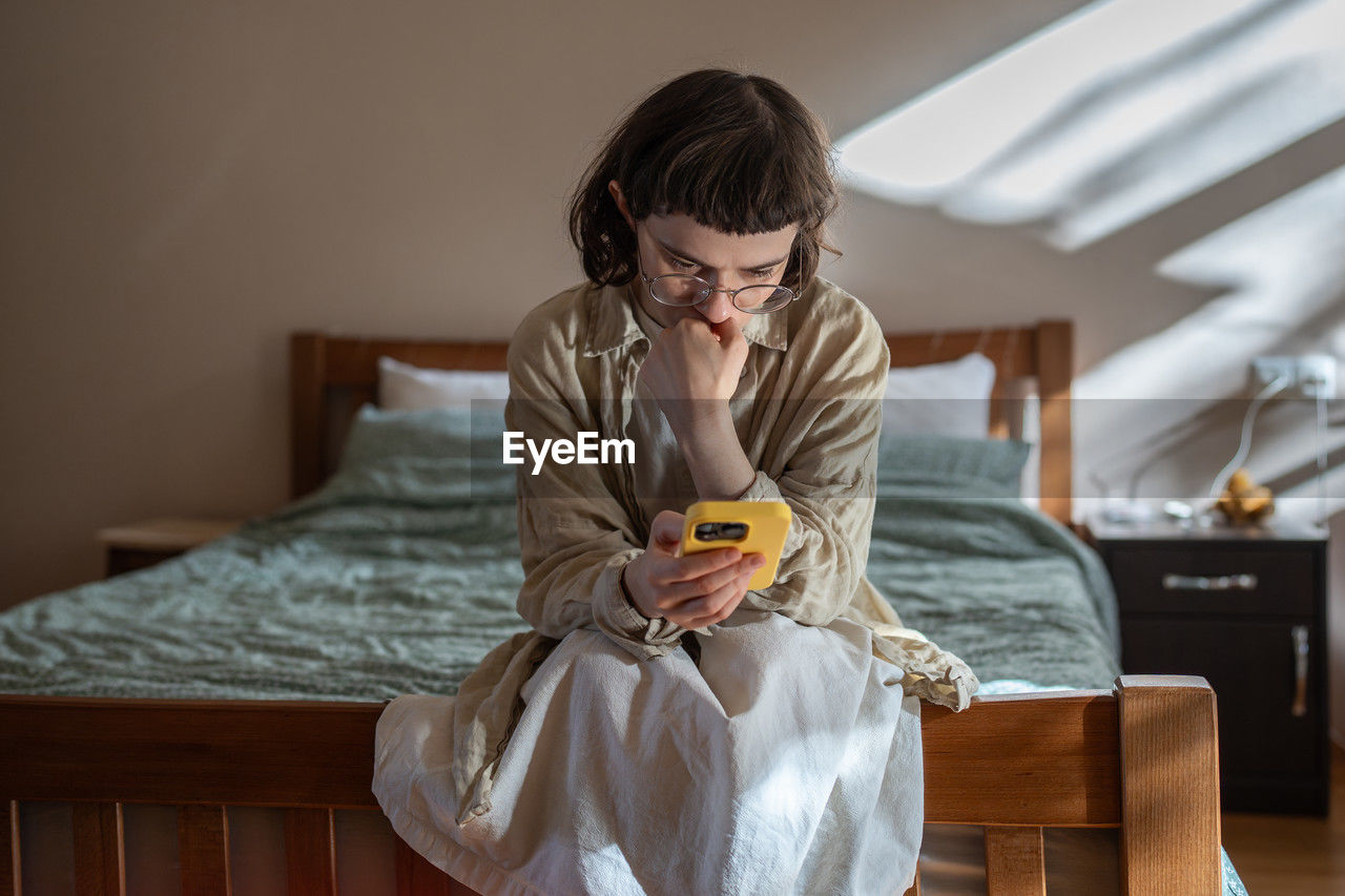 young woman using mobile phone while sitting on table