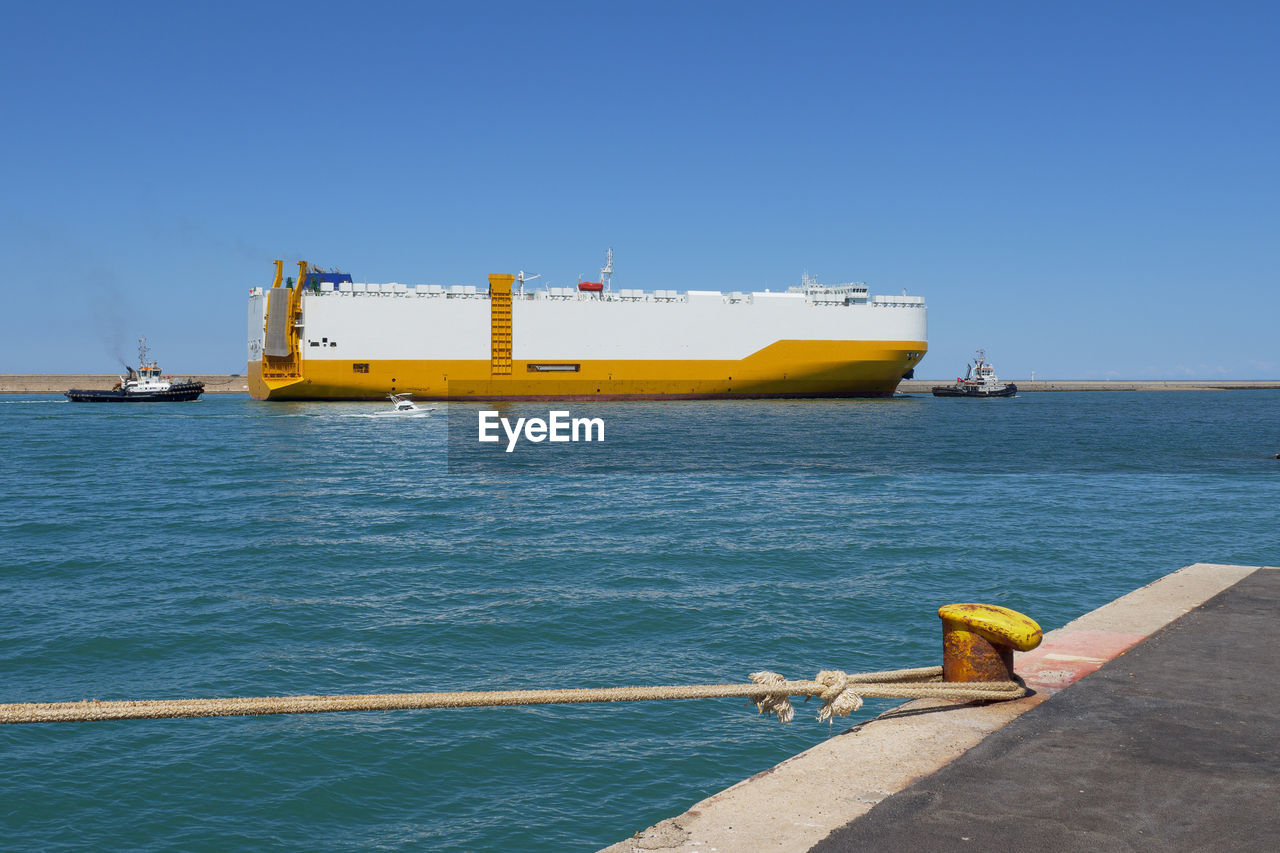 water, sea, transportation, ocean, nautical vessel, coast, vehicle, sky, blue, mode of transportation, ship, nature, clear sky, ferry, business, pier, industry, watercraft, boat, day, freight transport, copy space, sunny, shipping, bay, freight transportation, channel, outdoors, no people, sunlight, beach, travel, architecture, cargo ship, shore, container, land, business finance and industry, container ship