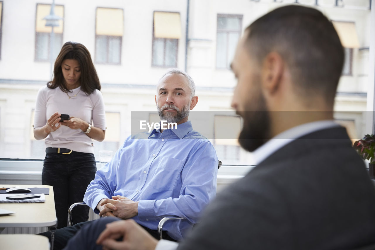 Mature businessman explaining with colleague in meeting at office