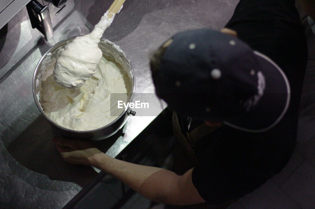 High angle view of woman mixing dough in bowl