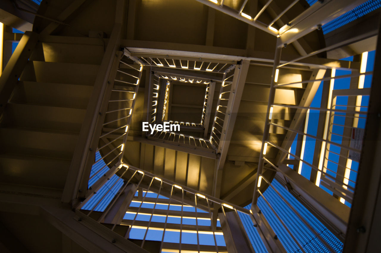 LOW ANGLE VIEW OF SPIRAL STAIRCASE IN ILLUMINATED BUILDING