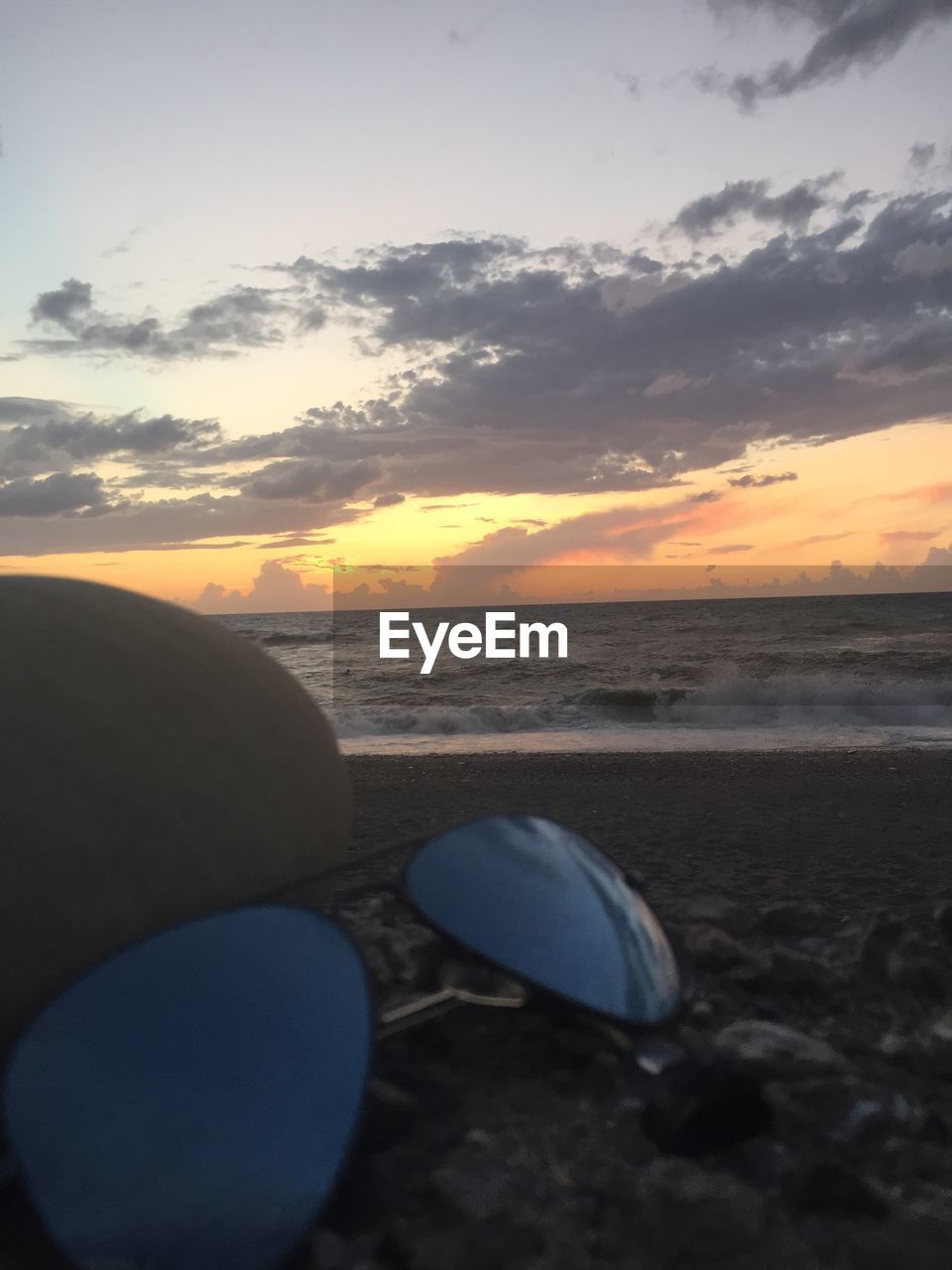 CLOSE-UP OF SEA SHORE AGAINST SKY DURING SUNSET