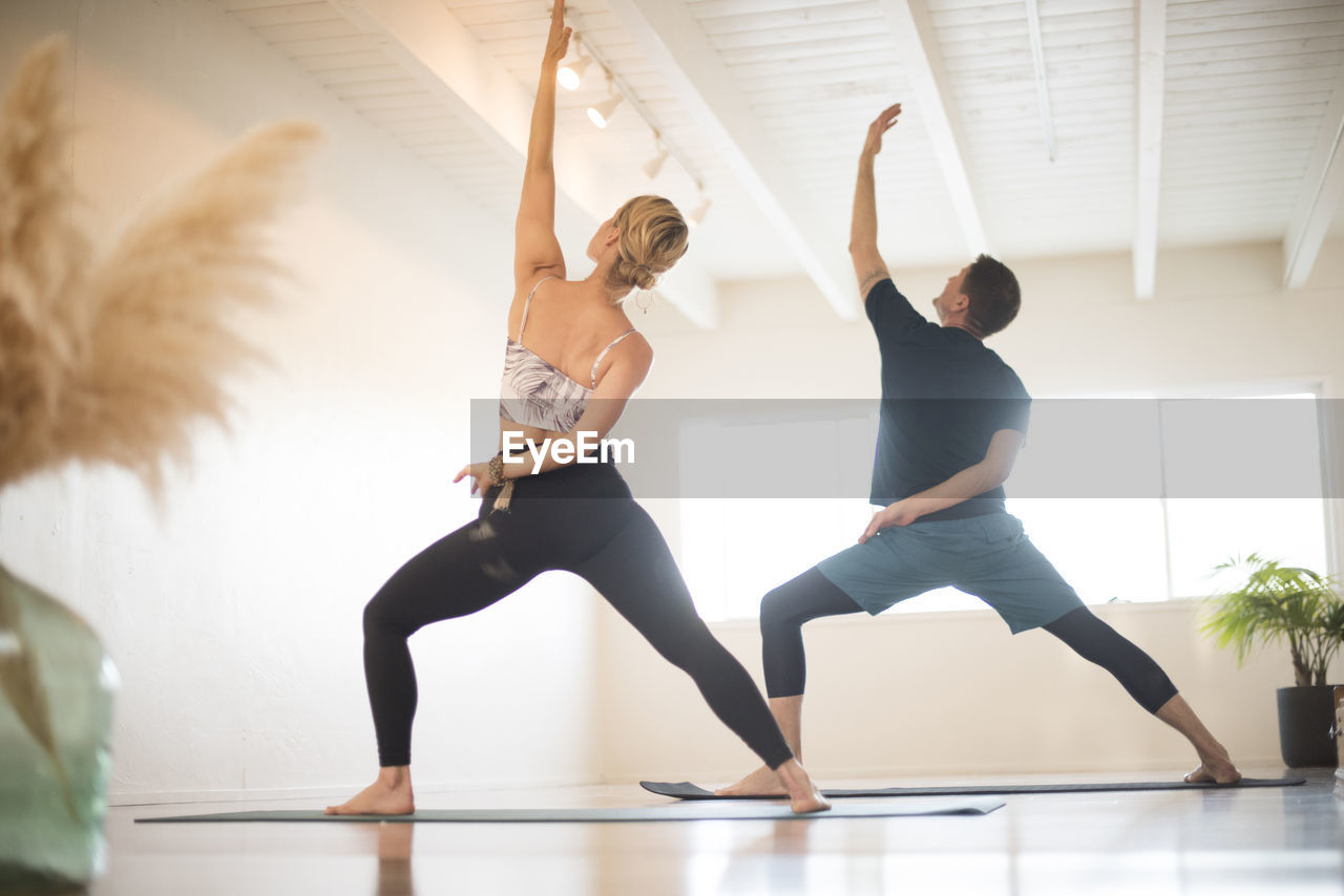 A couple in reverse warrior pose during yoga.