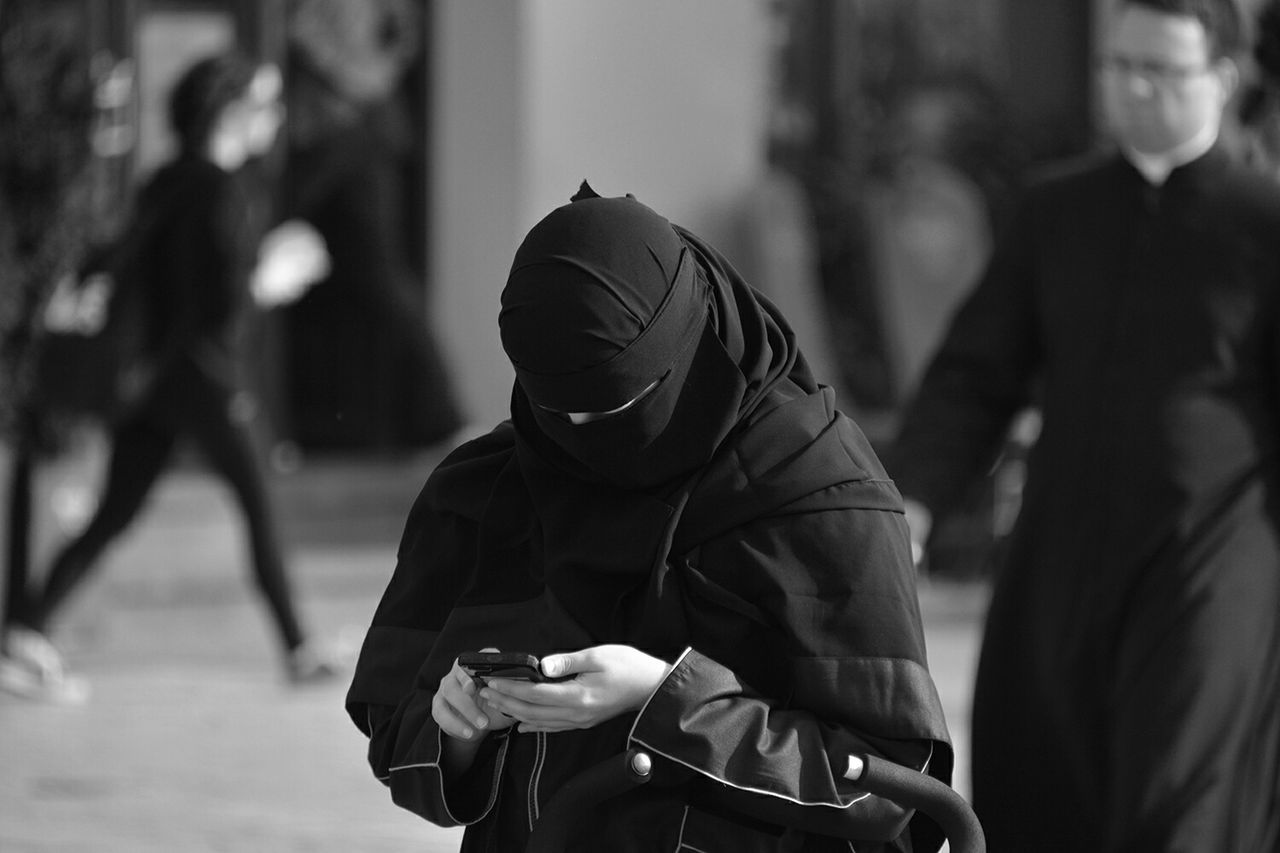 Woman in hijab using phone on street