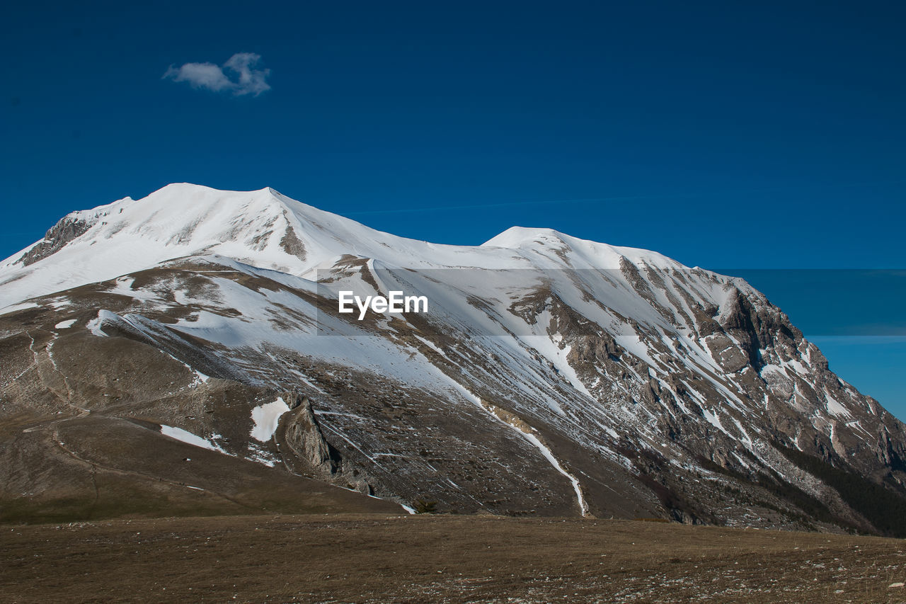 Scenic view of snowcapped mountains against blue sky