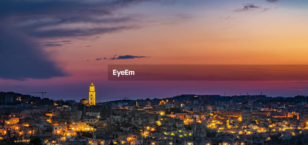 AERIAL VIEW OF ILLUMINATED CITY AGAINST CLOUDY SKY