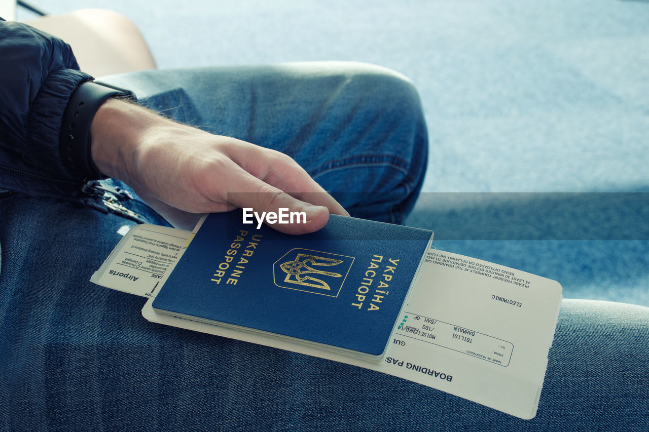 Midsection of passenger holding passport and ticket