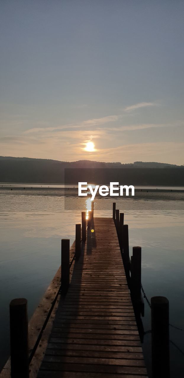 Wooden pier over lake against sky during sunset