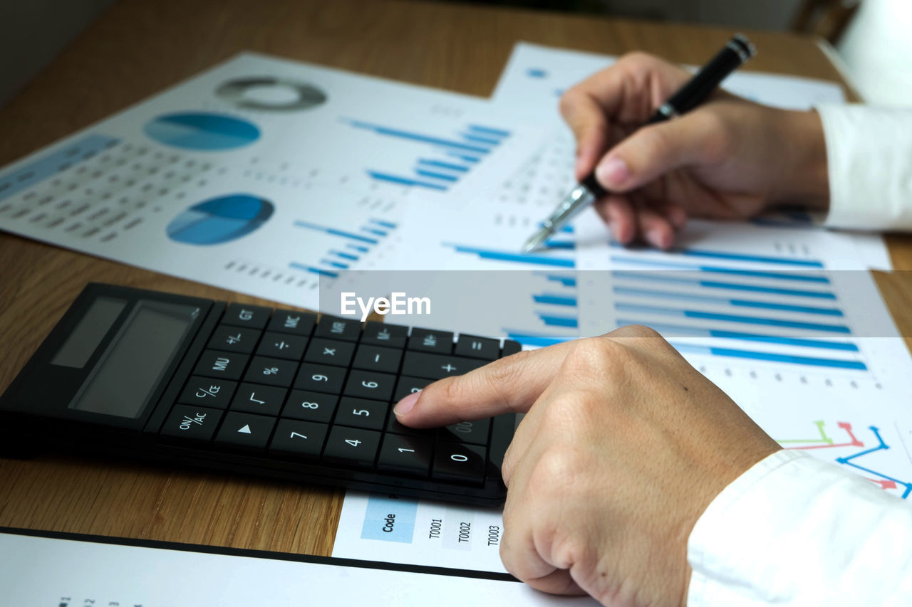 Cropped hands of business person working at desk in office