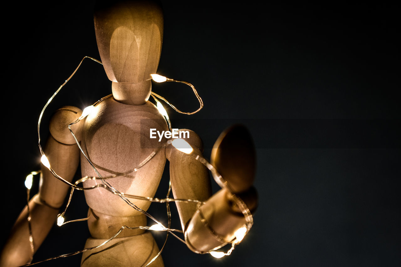 Close-up of wooden figurine with illuminated lights over black background