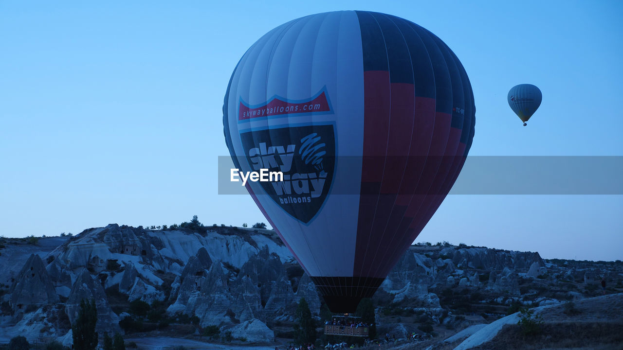 hot air balloon, balloon, air vehicle, hot air ballooning, aircraft, vehicle, transportation, sky, mid-air, blue, nature, adventure, flying, travel, mountain, snow, environment, mode of transportation, clear sky, scenics - nature, landscape, rock, travel destinations, no people, winter, cold temperature, outdoors, journey, ballooning festival, tourism, beauty in nature, day