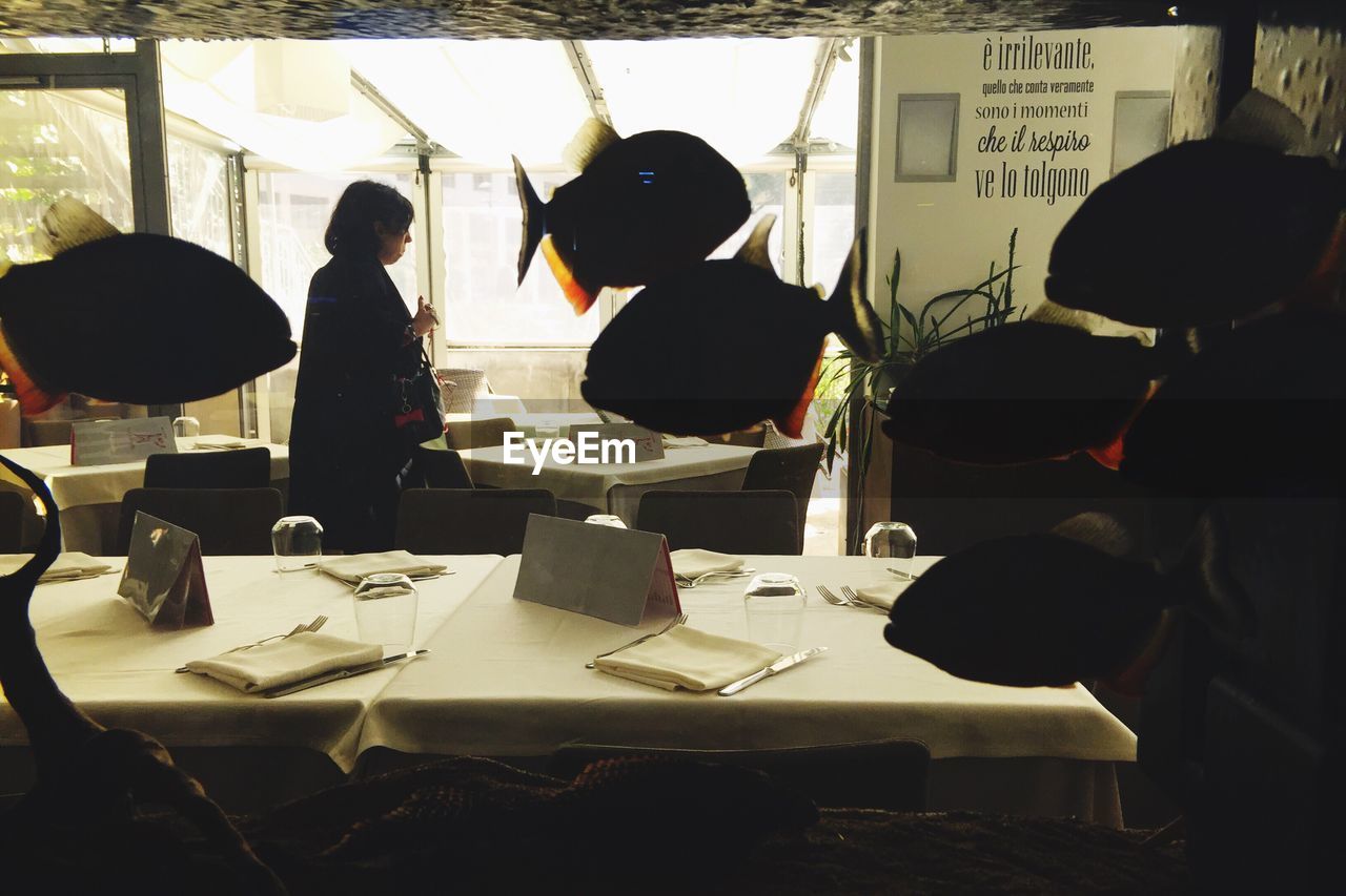 Woman in restaurant seen through fish tank