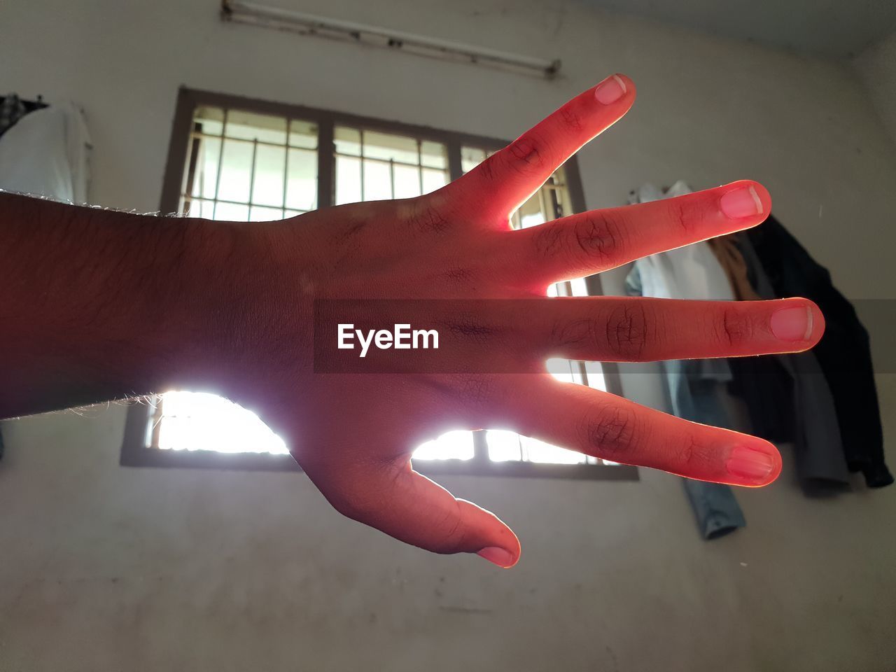 CLOSE-UP OF PERSON HAND ON RED WALL