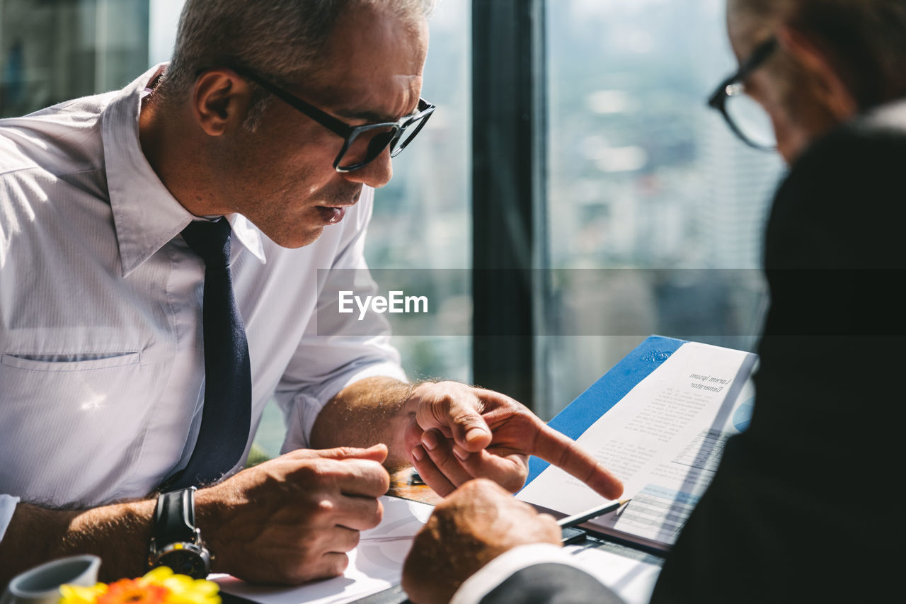 Man wearing eyeglasses having discussion with colleague in office