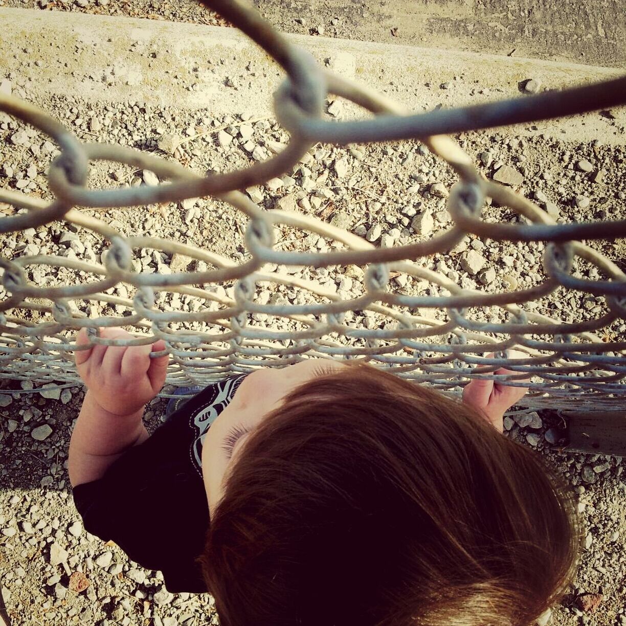 Elevated view of boy standing by chain link fence