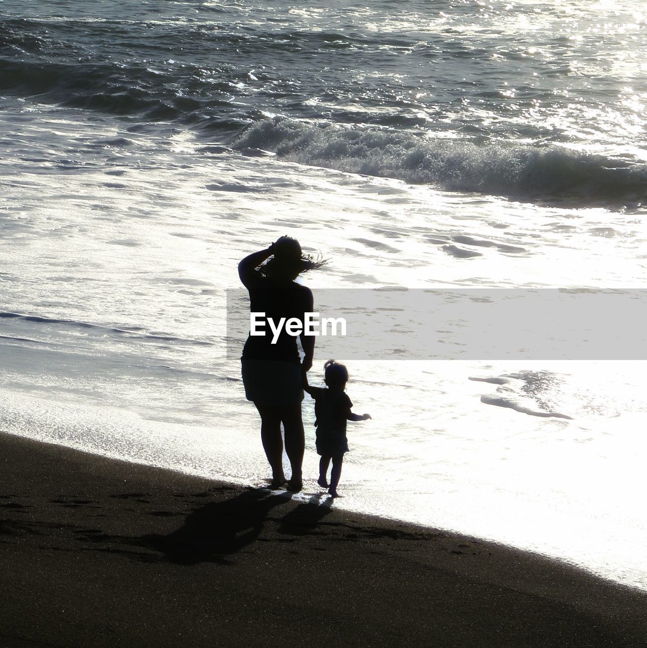 Full length of mother and daughter standing on beach