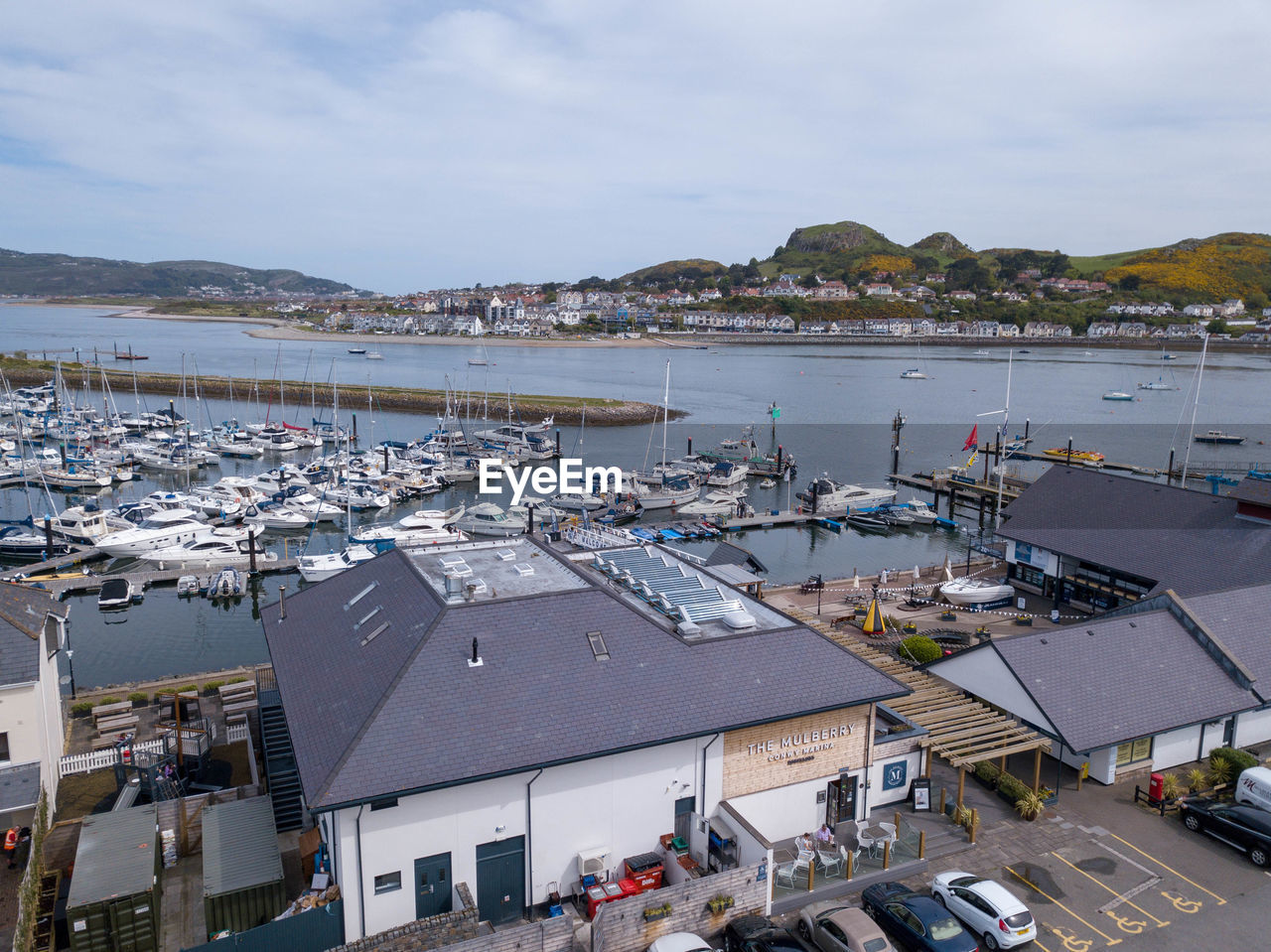 HIGH ANGLE VIEW OF BOATS MOORED AT HARBOR AGAINST BUILDINGS