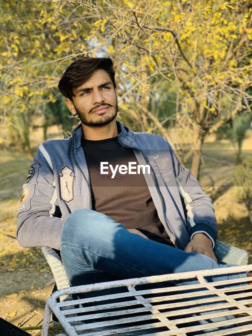 Young man looking away while siting outdoors