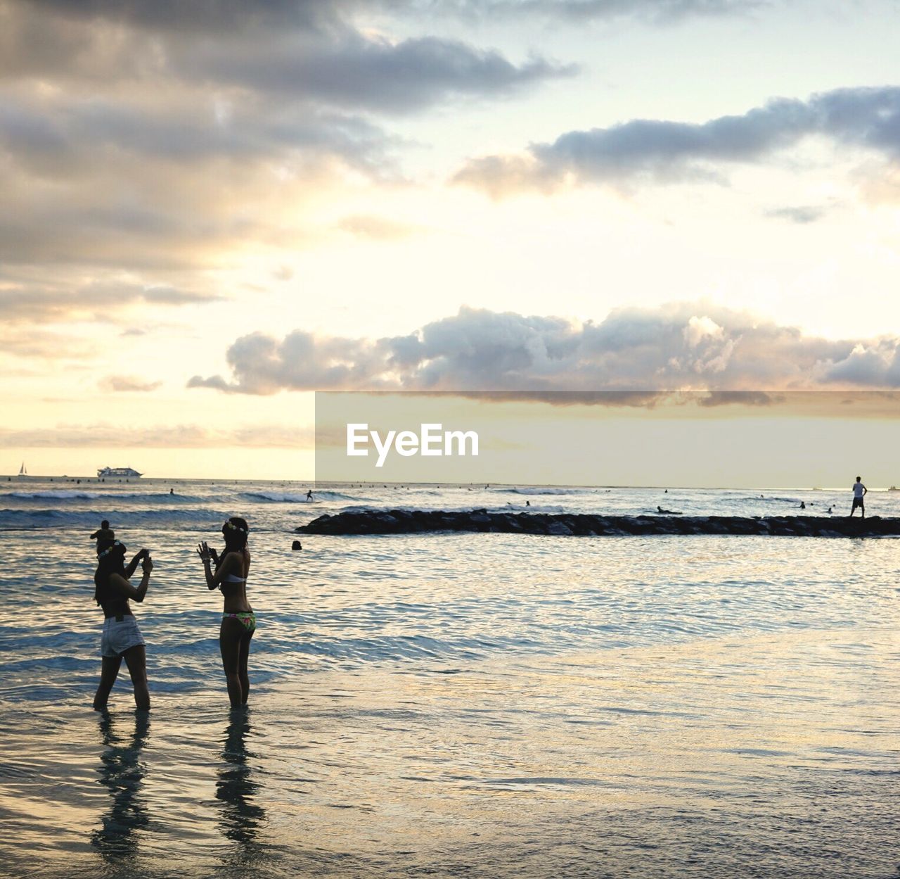 Young women in bikini enjoying at beach against cloudy sky