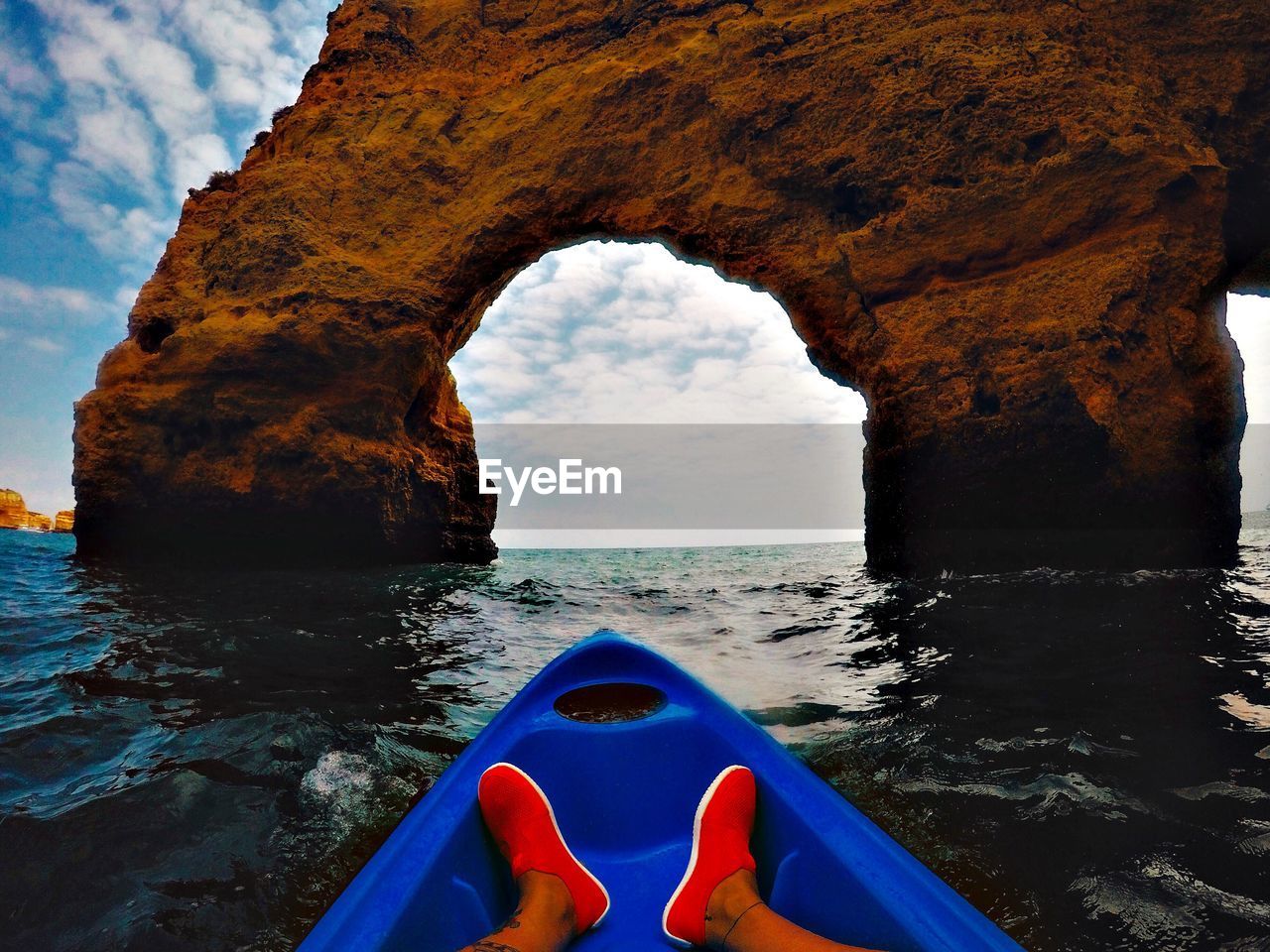 Low section of person traveling in boat against natural arch