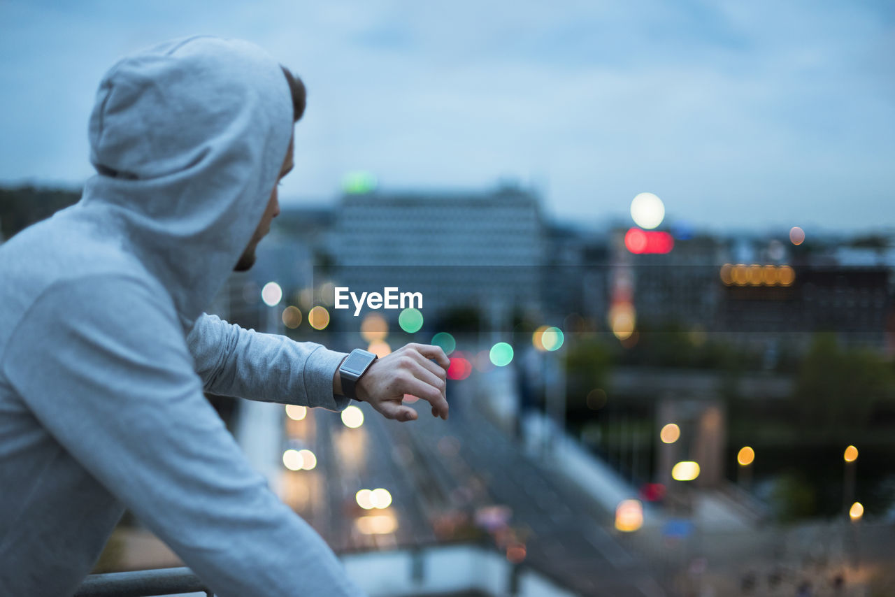 Athlete checking his smartwatch above the city at dawn