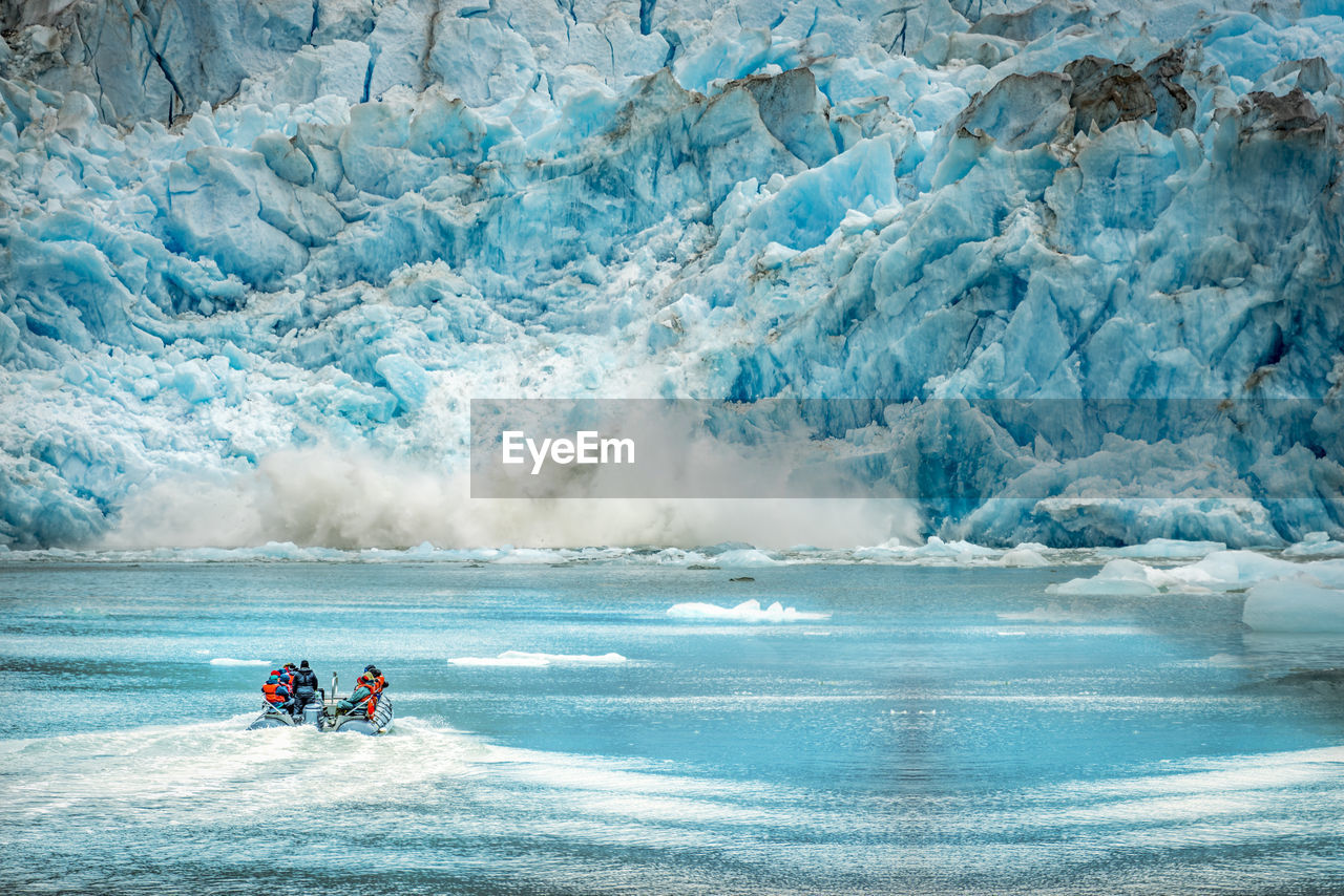 People in boat on river against frozen mountain