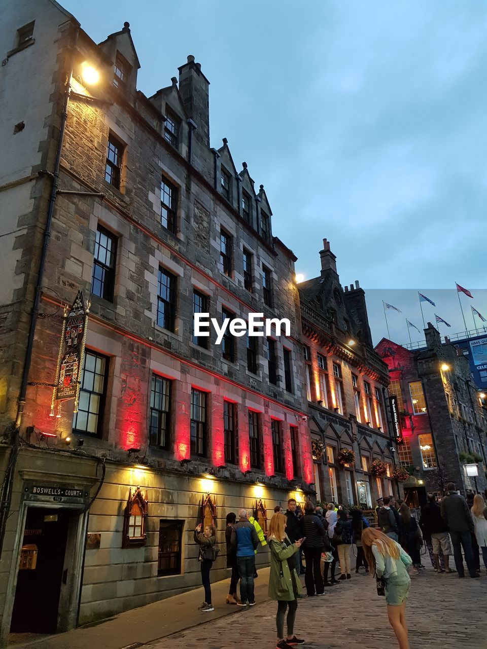 LOW ANGLE VIEW OF PEOPLE IN ILLUMINATED CITY